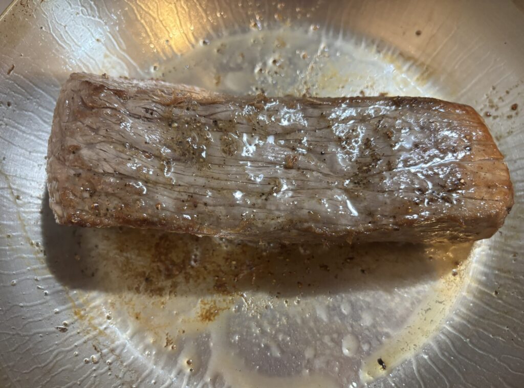 フライパンで牛もも肉ブロックを焼いている