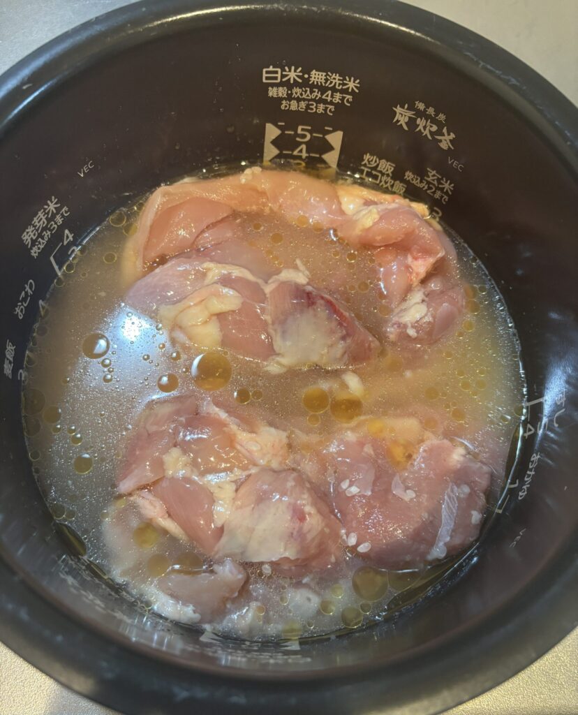 炊飯釜に鶏もも肉、調味料を入れた様子