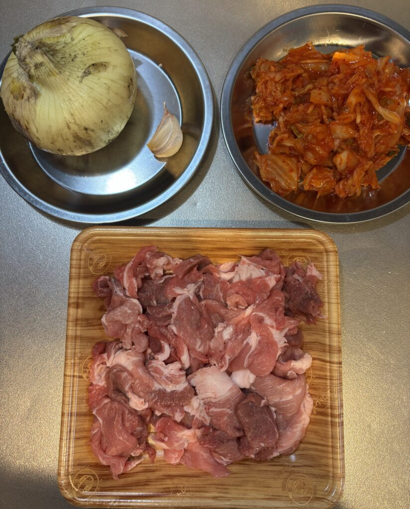 スンドゥブ作成前の豚キムチの材料一覧(玉ねぎ、にんにく、キムチ、豚肉)
