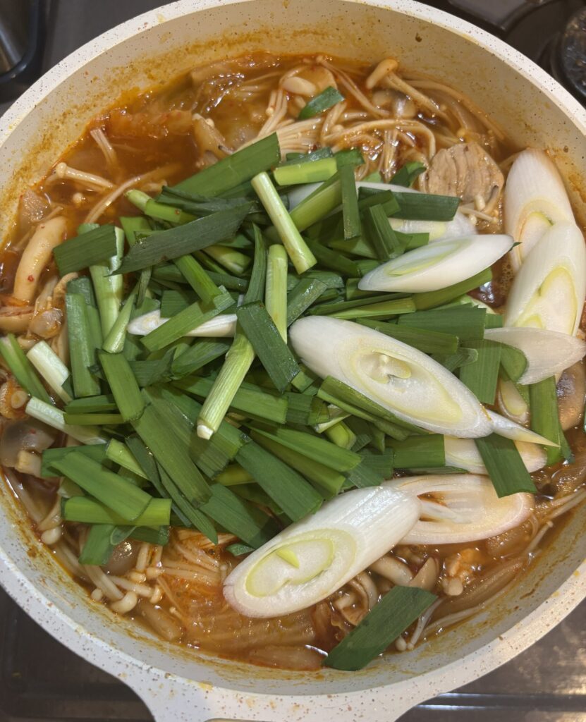 豚キムチに水を入れた後にえのき、しめじ、にら、長ねぎを入れた様子
