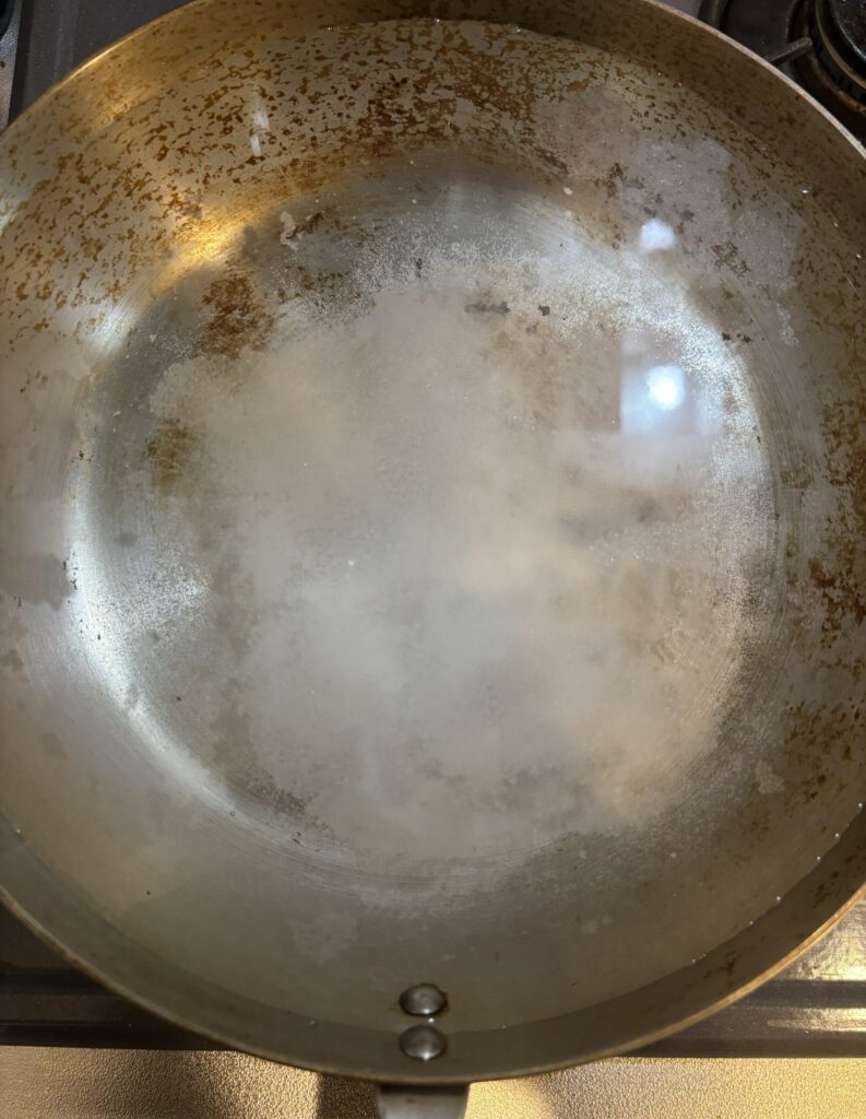 ステンレスフライパンに水と重曹を入れている