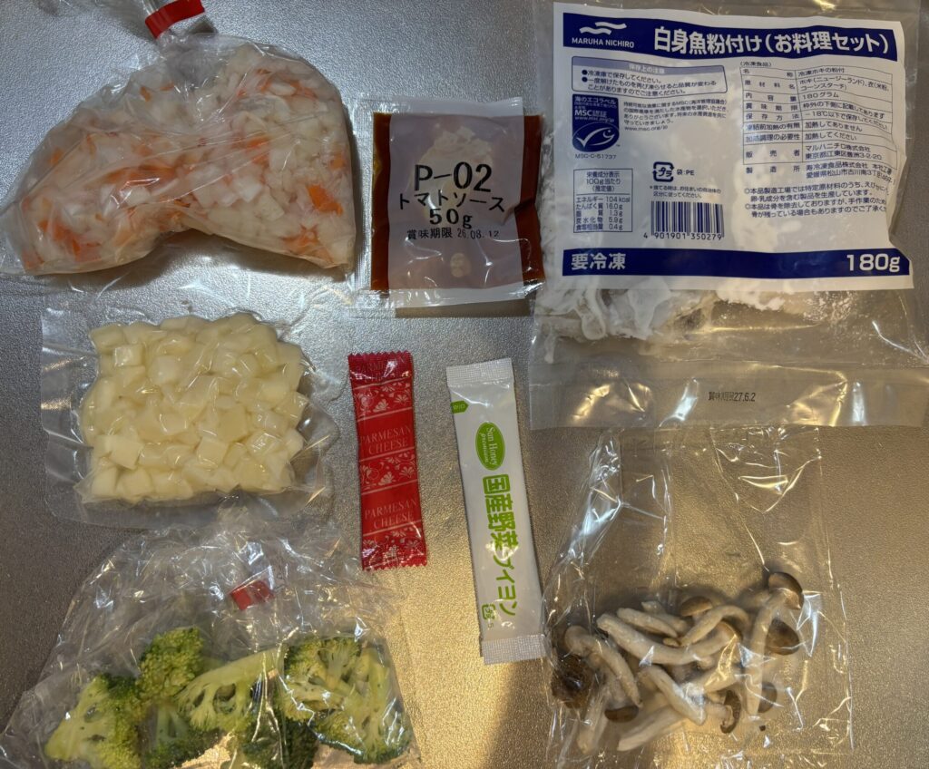 パルシステムミールキットの中身。
細かく切られた玉ねぎ、にんじん、ジャガイモ、ブロッコリー、しめじ、調味料、冷凍白身魚がある。